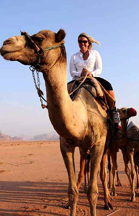 Photo of award-winning author K.J. Howe riding a racing camel in Jordan. Photo credit: K.J. Howe