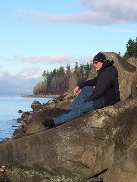 Dr. Mark Seely, author of Stones: Meditations on Human Authenticity, sitting on a rock at Point Beach
